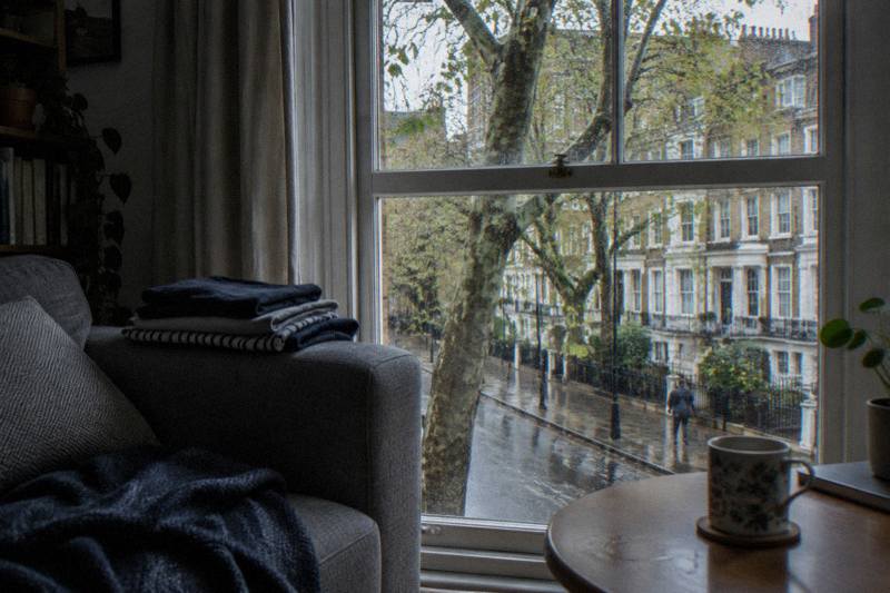 Sofa by a rain streaked sash window in a compact apartment