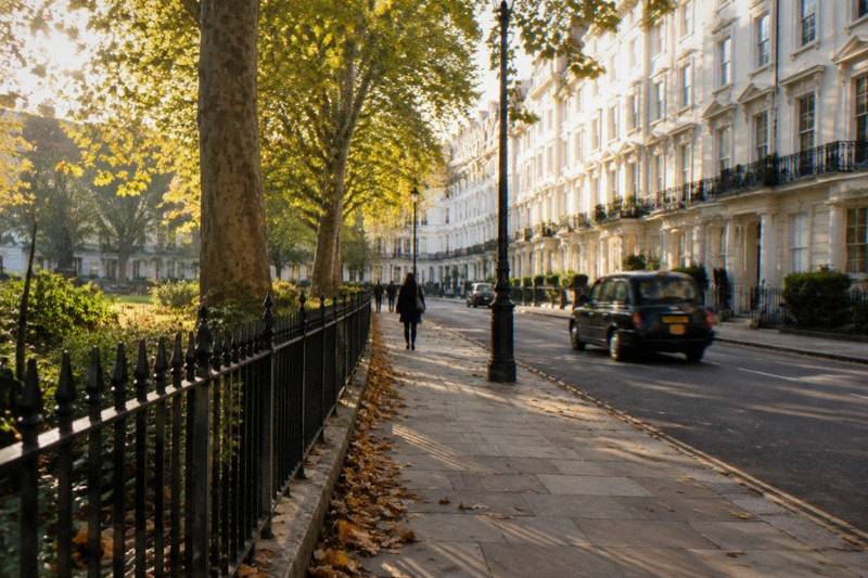 White stucco terraces glowing in late afternoon light near Bayswater station, a black cab passing
