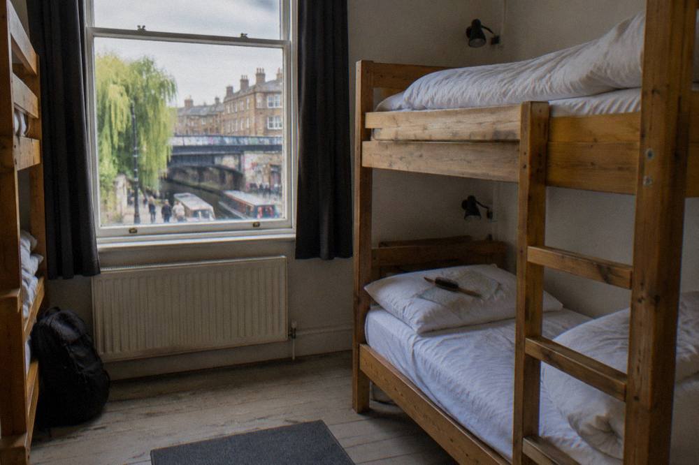 A tidy six-bed hostel dorm with wooden bunk beds and individual reading lights