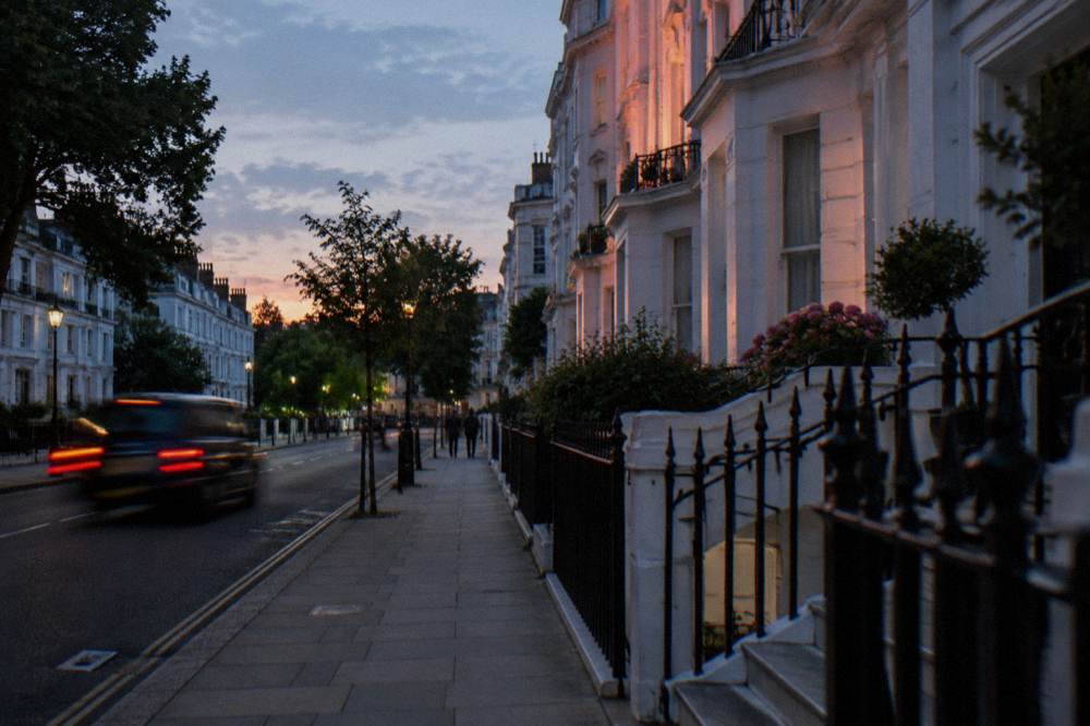 A London residential street with white stucco terraced houses at dusk