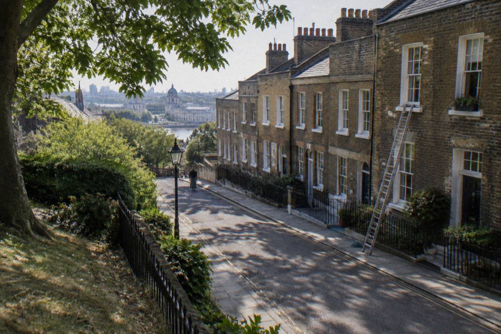 A narrow London street of brick townhouses with sash windows in bright daylight