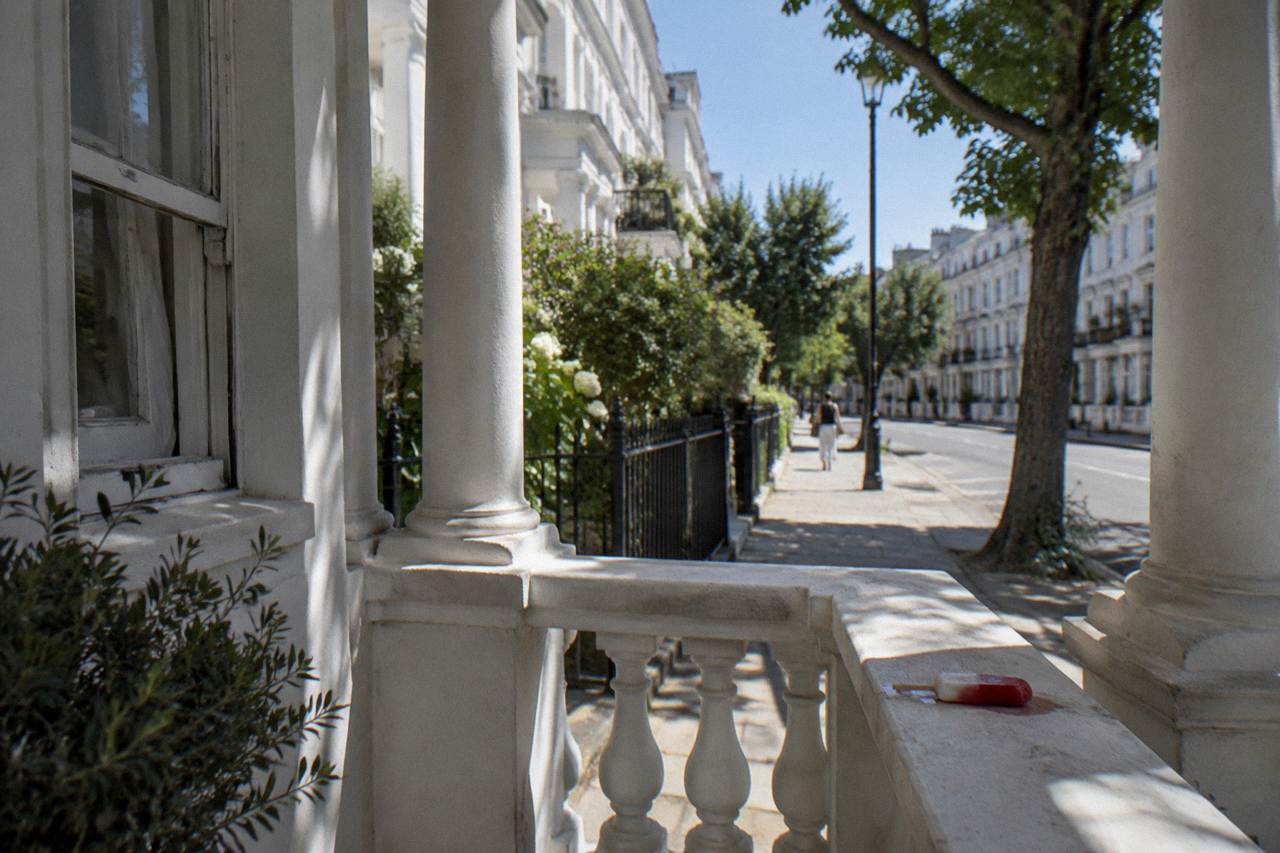 A London residential street with white stucco terraces under a clear summer sky