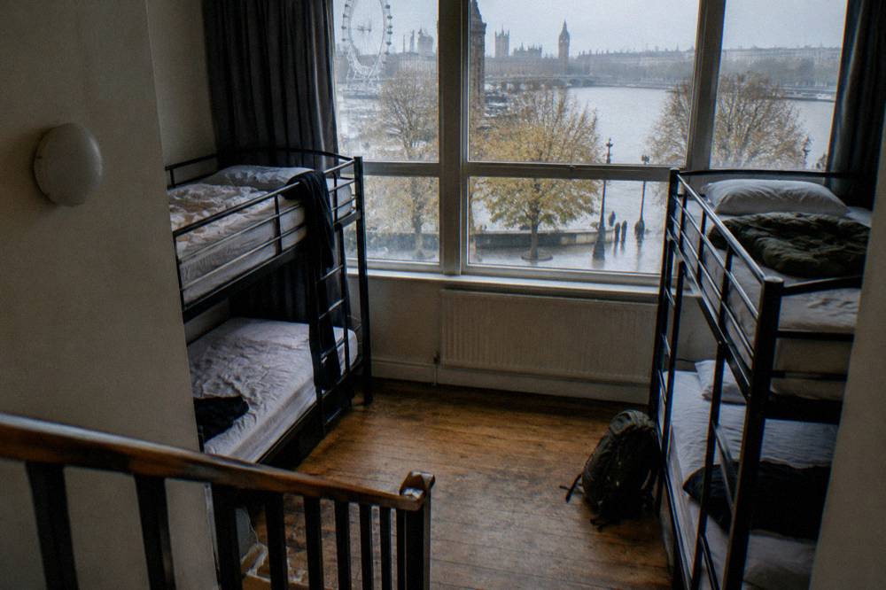 A bunk dorm room with four metal bunks, individual reading lights and wooden floor