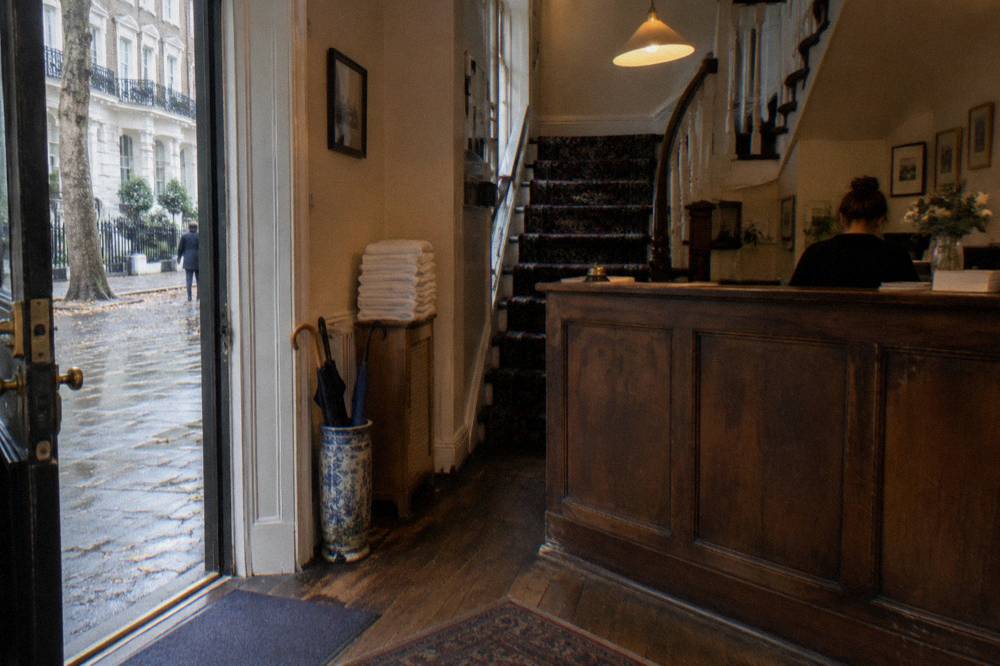 A small budget hotel reception with a wooden counter and staircase