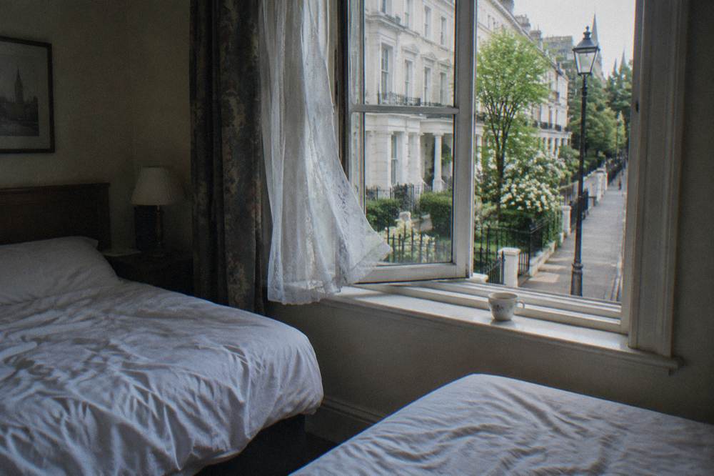 A twin hotel room with two single beds and a window onto a quiet street