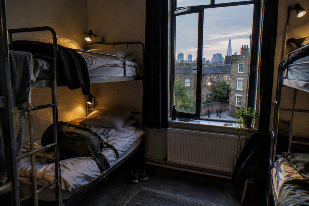 A bunk dorm room with four metal frame beds and personal reading lights