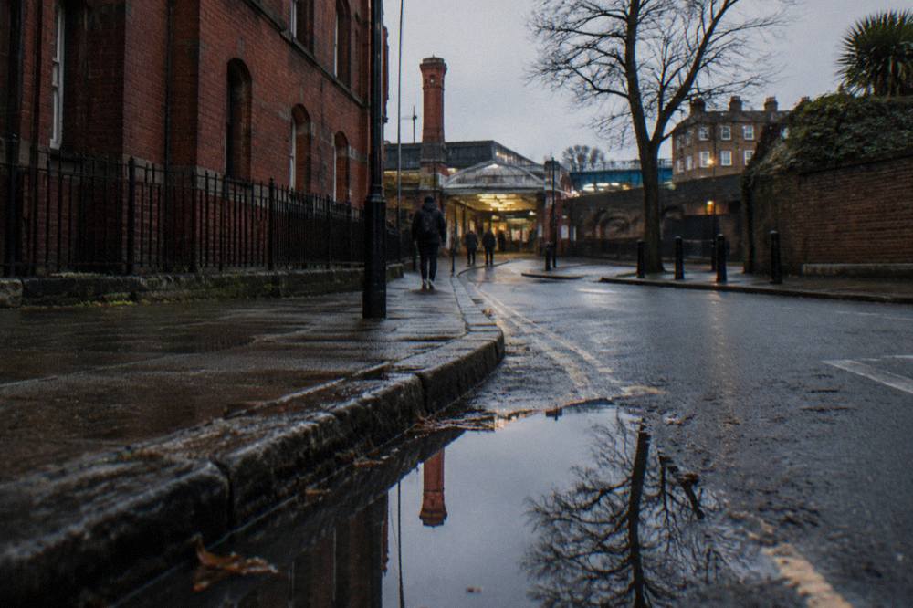 A London street corner with a red brick building and a station entrance in the distance