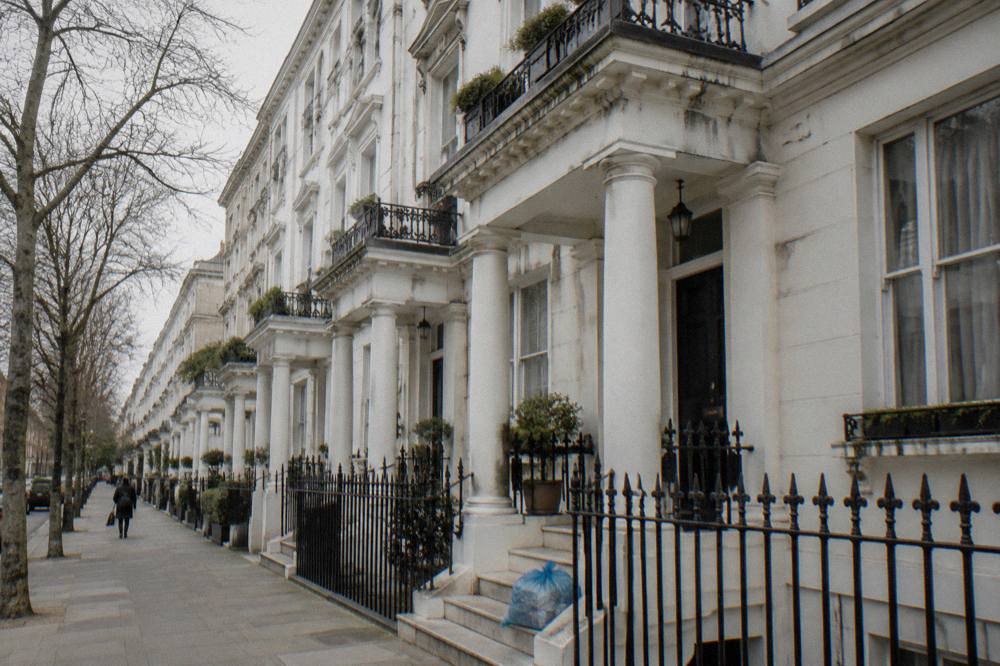 A London street of tall white stucco terraced houses with columned porches