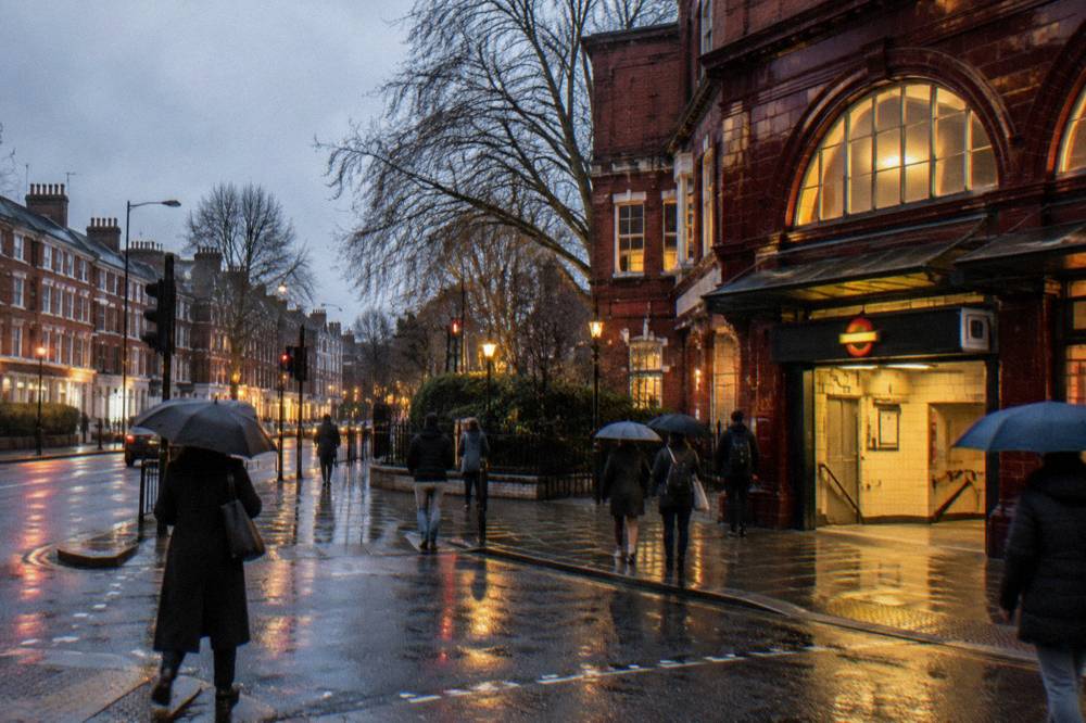 A tube station entrance on a busy west London road with terracotta brick buildings behind