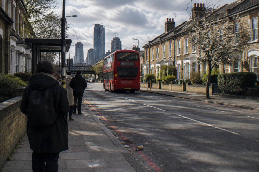 A red London bus on a street with terraced buildings either side