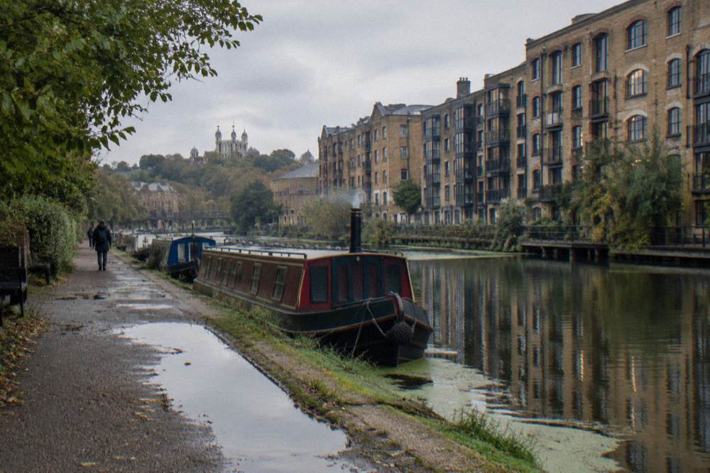 A canal-side path in East London with warehouse conversions and moored narrowboats