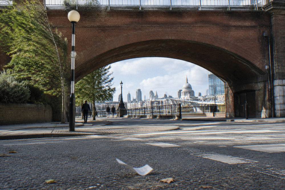 A city road with a red brick railway arch and a pedestrian crossing in London