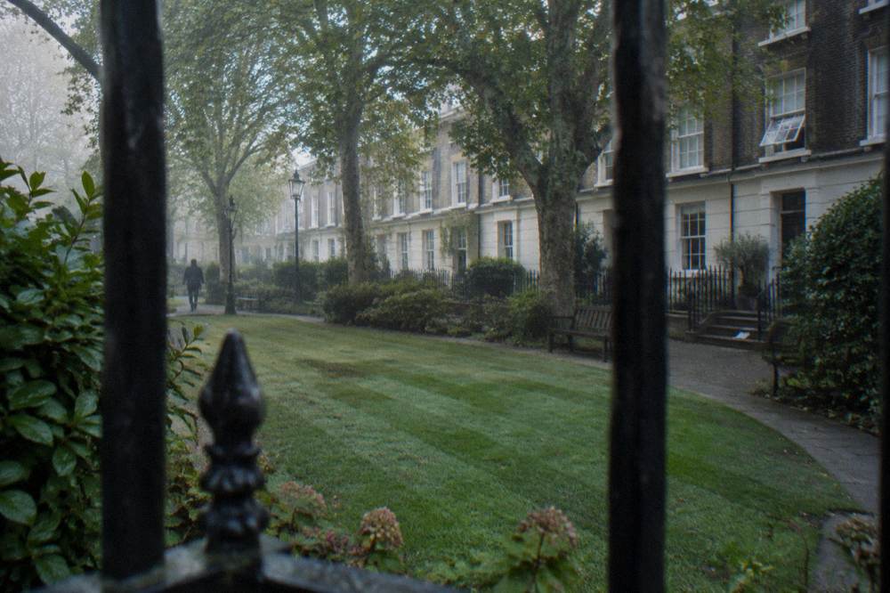 A residential London square with brick townhouses and parked bicycles