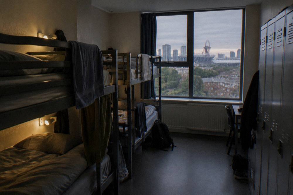 A shared hostel dorm room with bunk beds, individual lockers and a reading light by each pillow