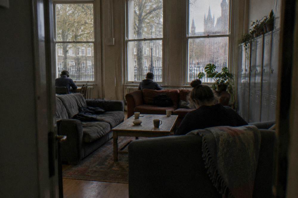 A hostel common room with sofas, low tables and lockers along one wall