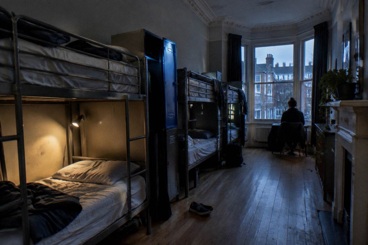 A bunk dorm room with metal frame beds and personal reading lights in a city hostel