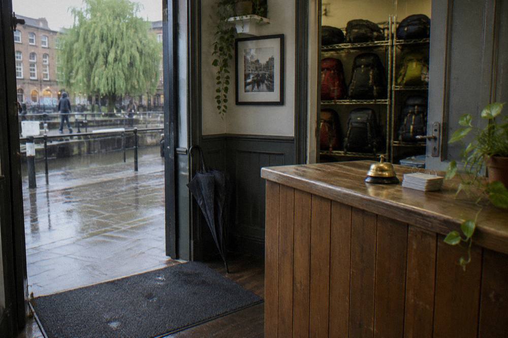 A hostel reception desk with a luggage storage room behind it