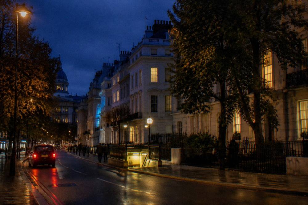 A London street at night with terraced houses and a lit station entrance