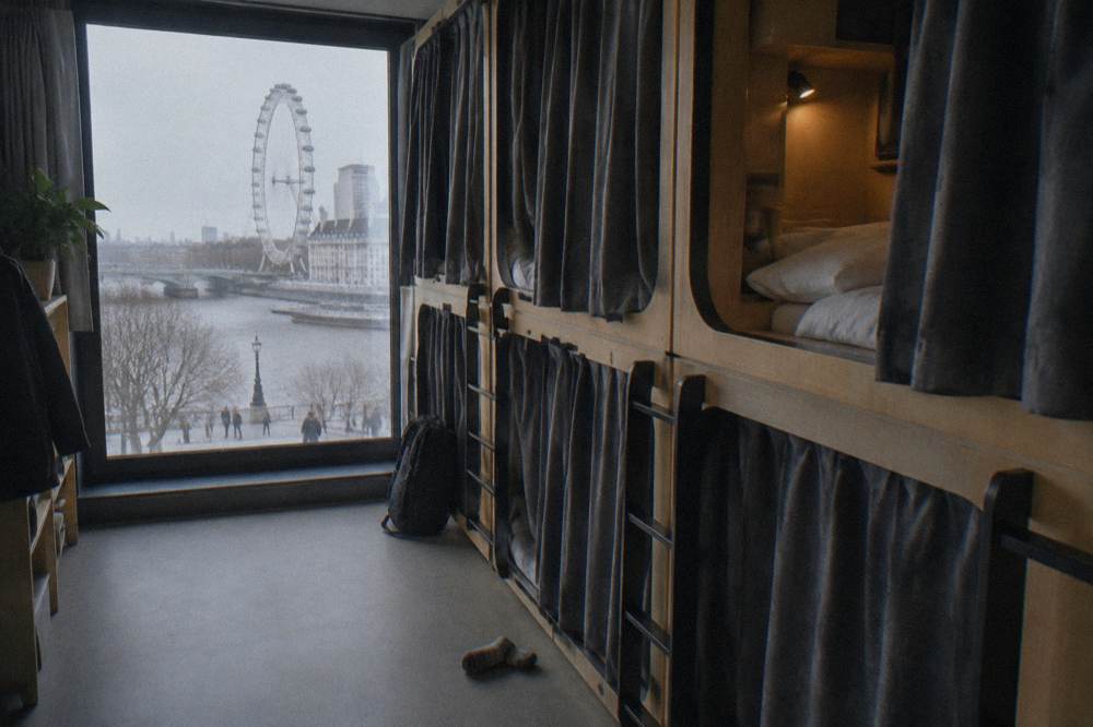 A row of capsule pods with privacy curtains in a hostel dorm
