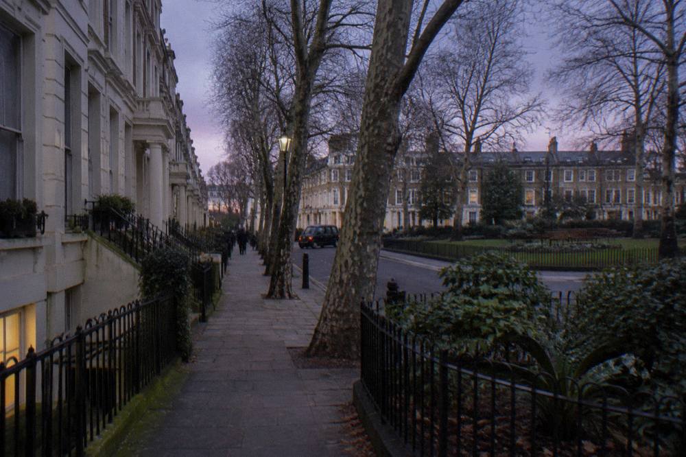 A row of white stucco townhouses along a quiet London garden square