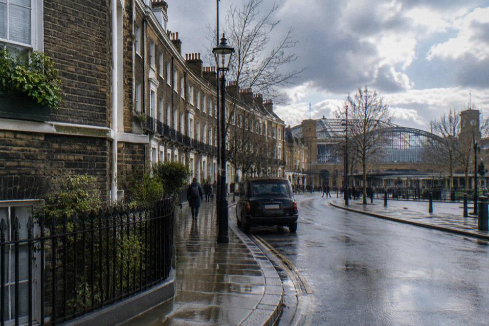A curved London street with a station exterior and terraced brick facades