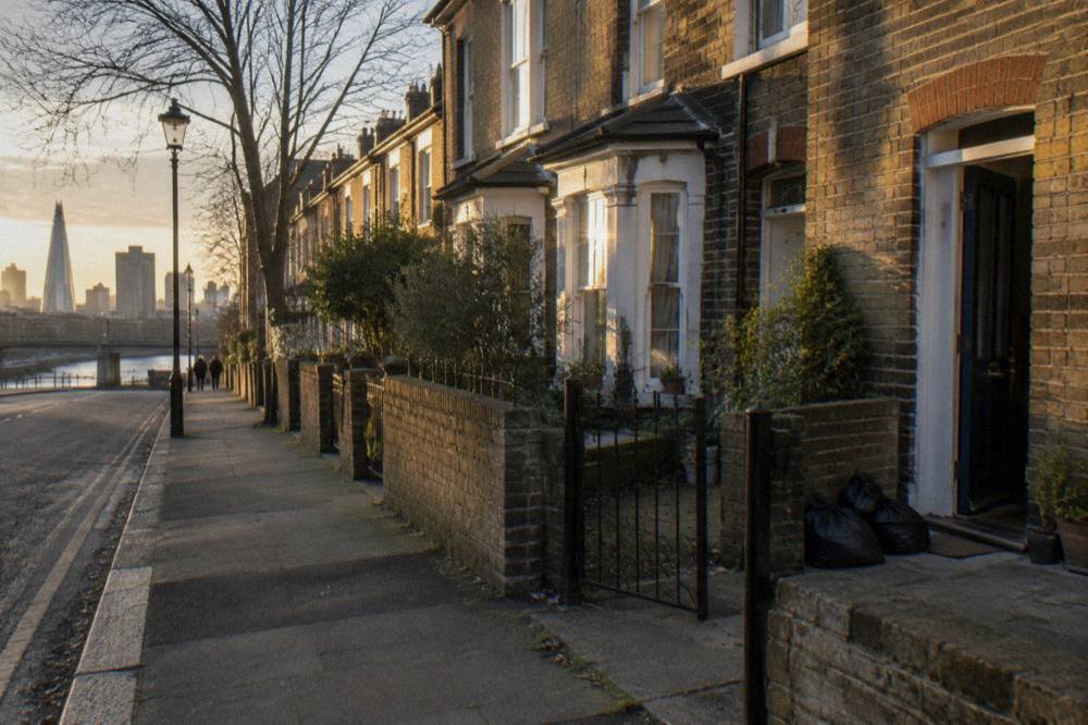 A London street with terraced houses and parked cars under evening light