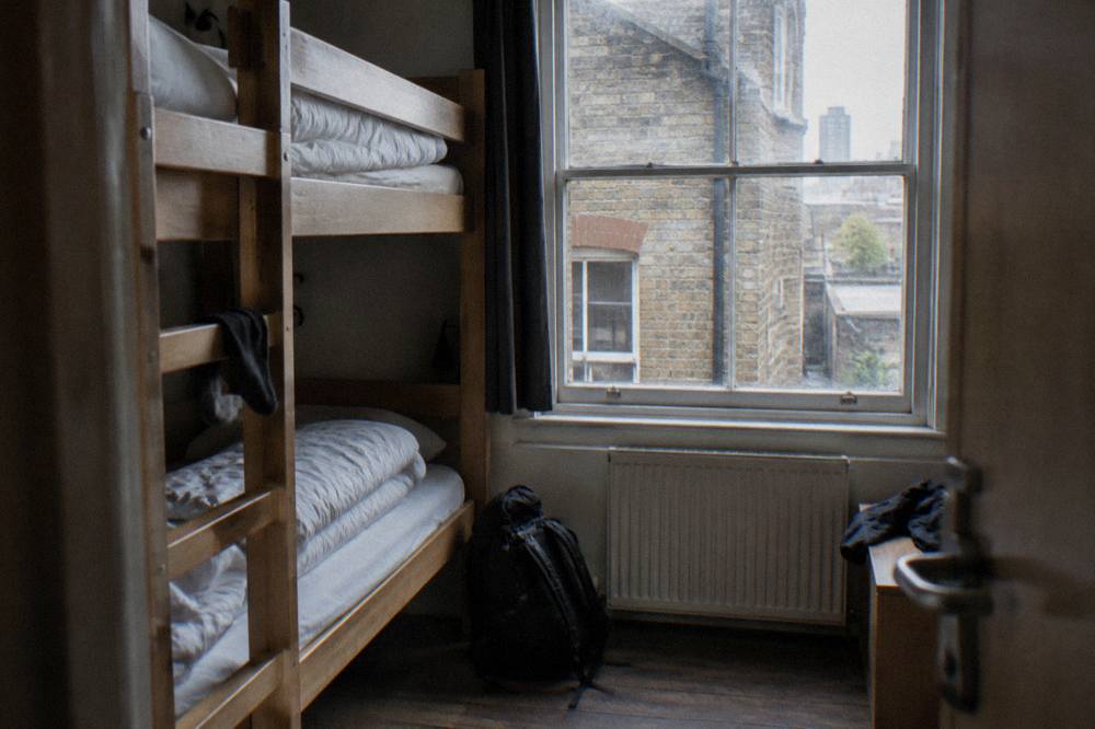 A hostel dorm room with wooden bunk beds and a ladder, empty and tidy