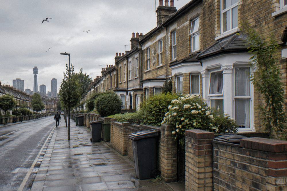 A residential London street of brick terraced houses under a grey sky