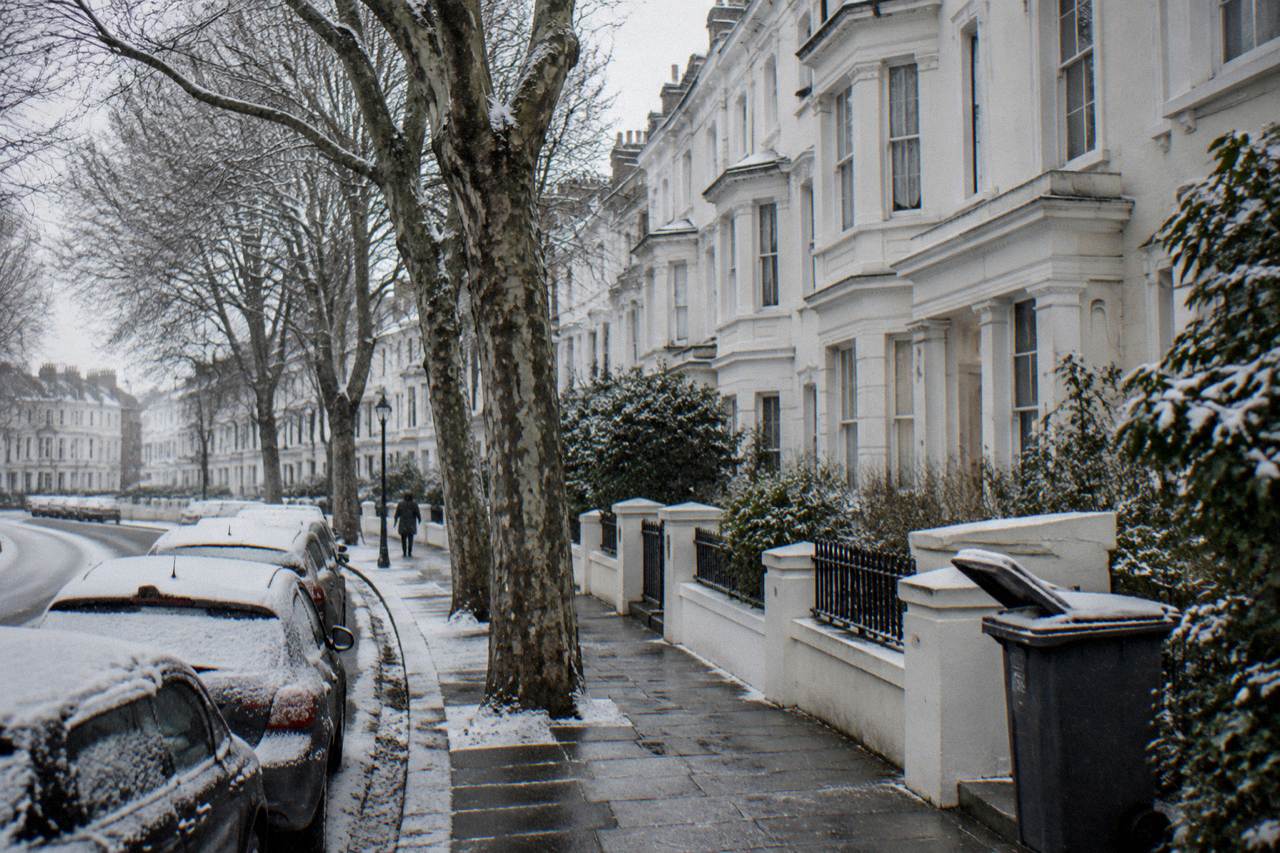 A quiet London residential street with terraced houses and parked cars on an overcast day