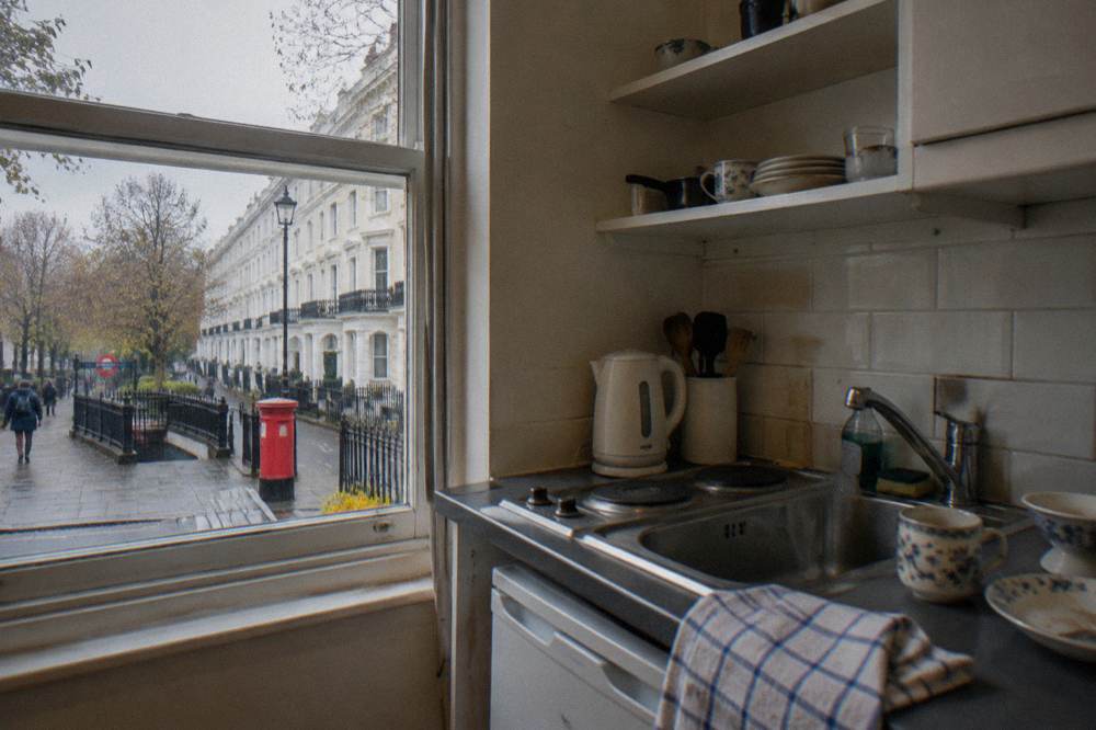 A kitchenette corner with a compact hob, sink, kettle and a few shelves of crockery