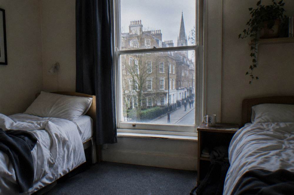 A twin hotel room with two single beds and bedside tables
