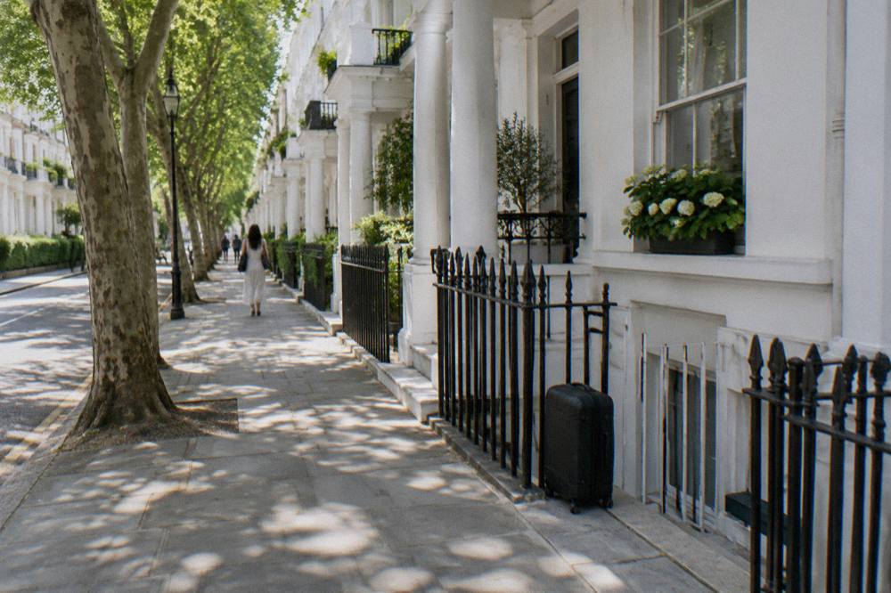 A narrow London street with white stucco terraces and parked cars in daytime