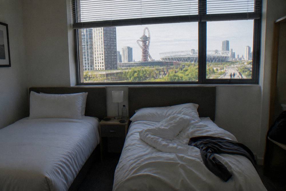 A compact hotel twin room with two single beds and neutral bedding