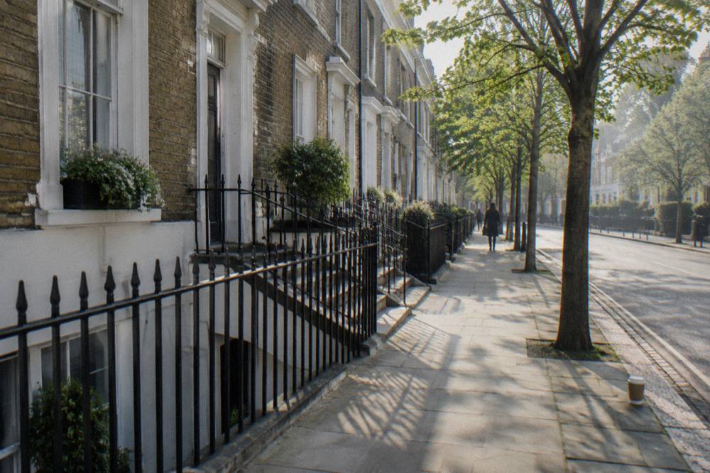 A narrow London residential street with brick terraced houses and trees