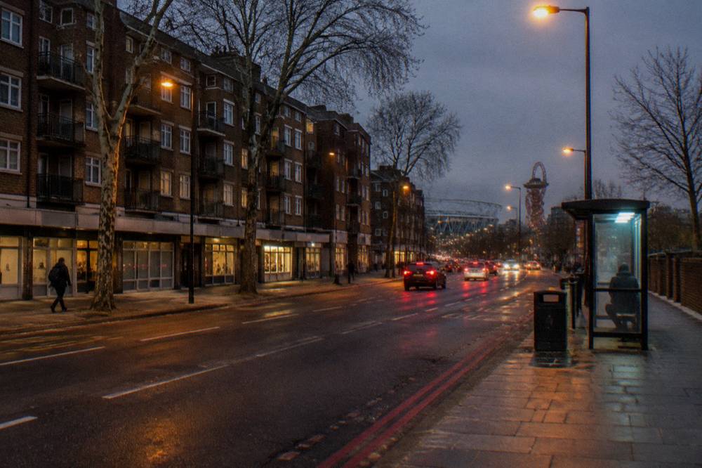 A wide London road with a brick apartment block and evening traffic