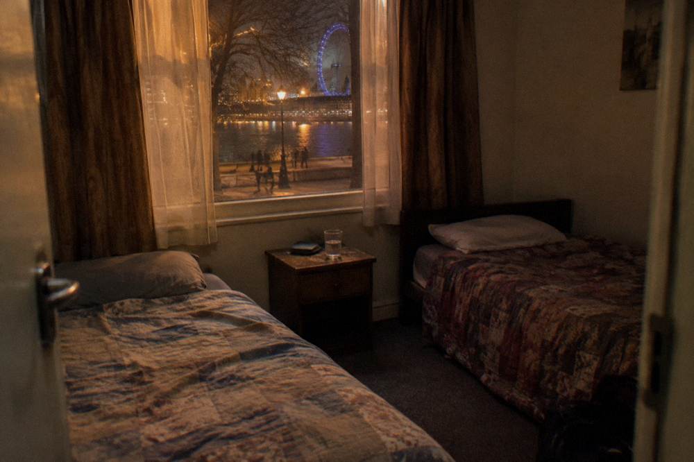 A twin hotel room with two single beds and a bedside table