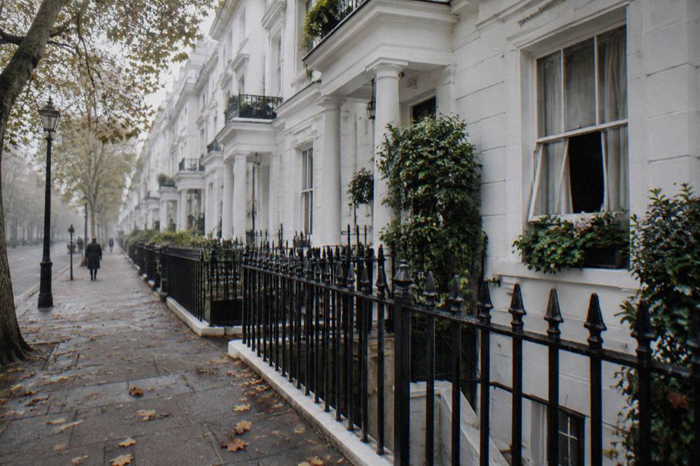 A tree-lined west London terrace of white stucco townhouses on a quiet afternoon