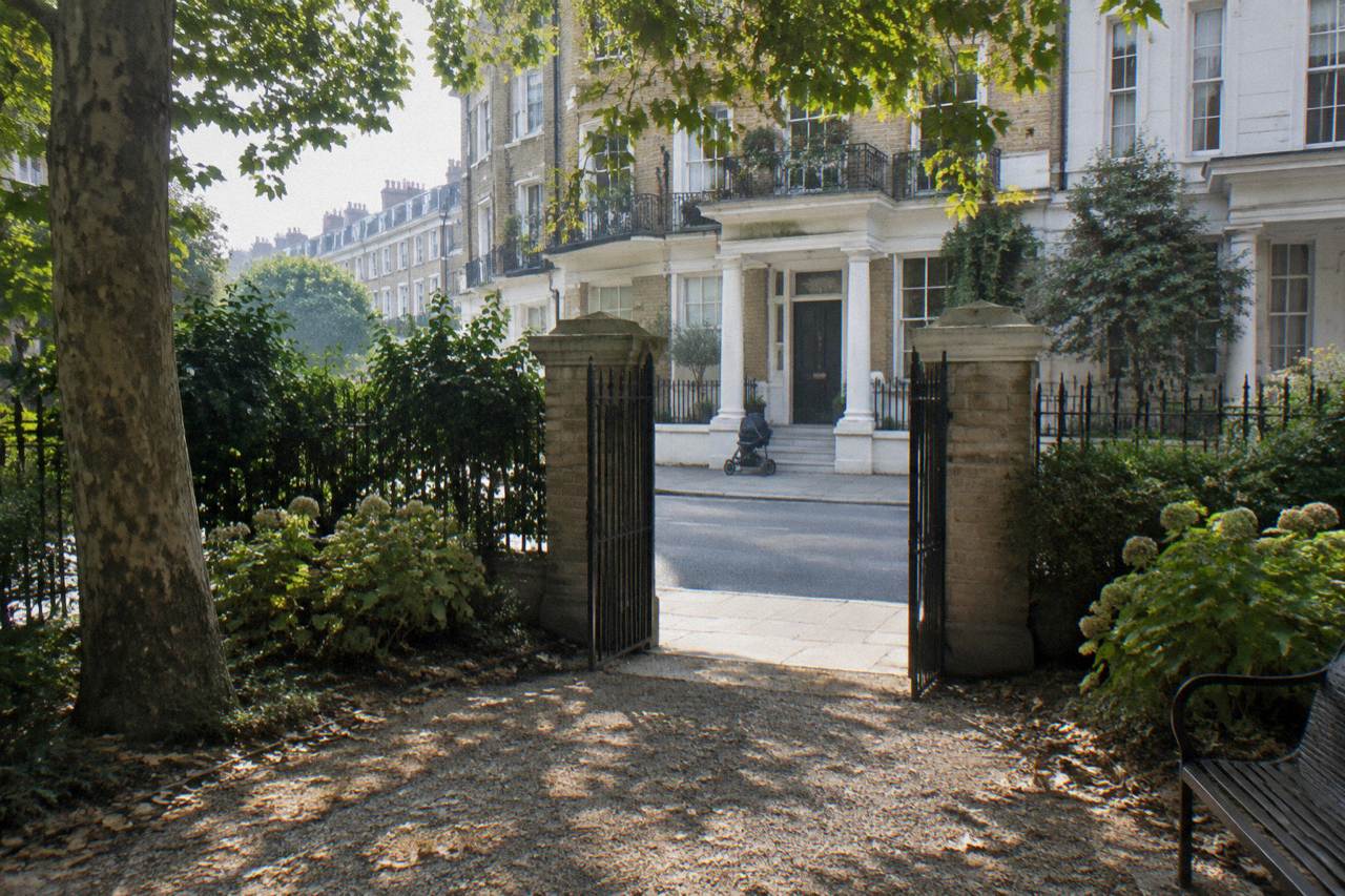 A quiet west London street of terraced townhouses near a garden square at midday