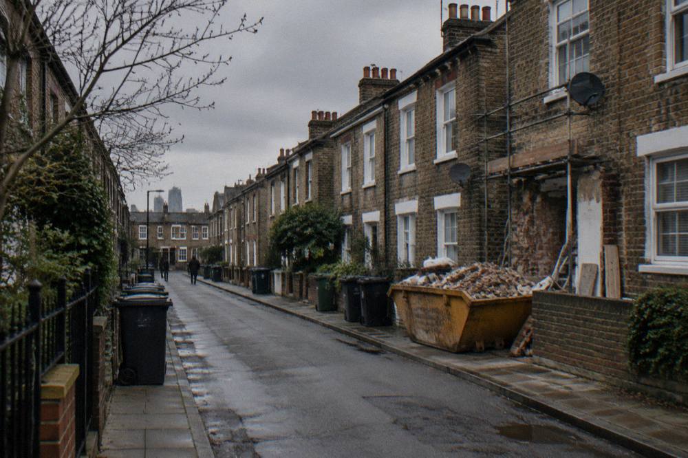 A narrow east London street of brick terraces under a grey sky