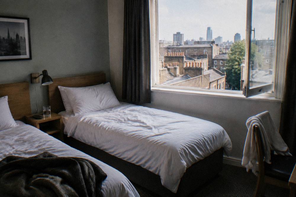 A twin hotel room with two single beds and a small bedside table