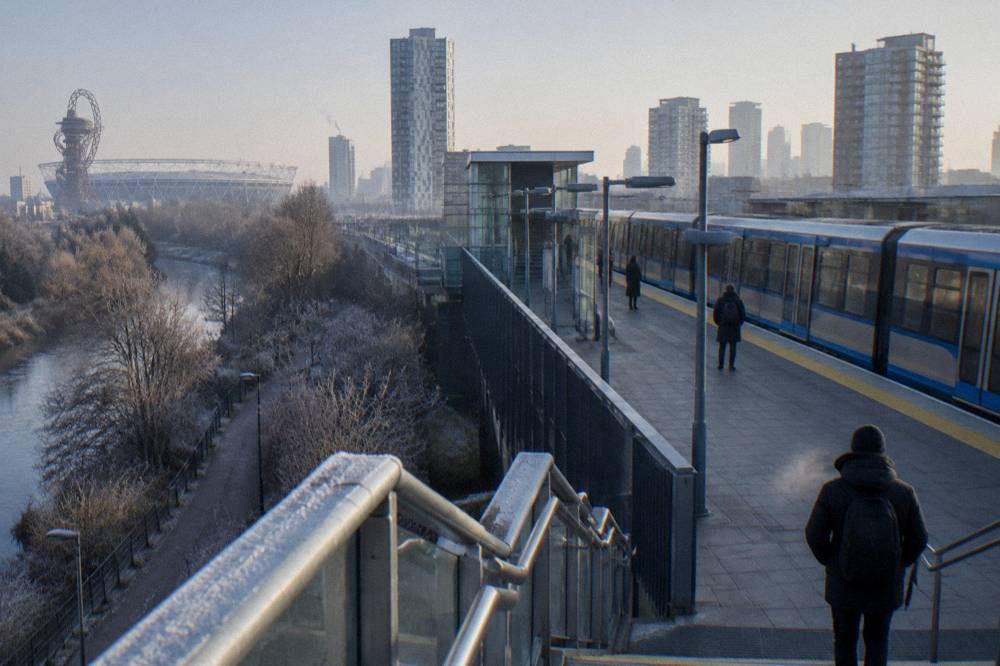 A DLR station platform in East London with elevated track and apartment blocks behind