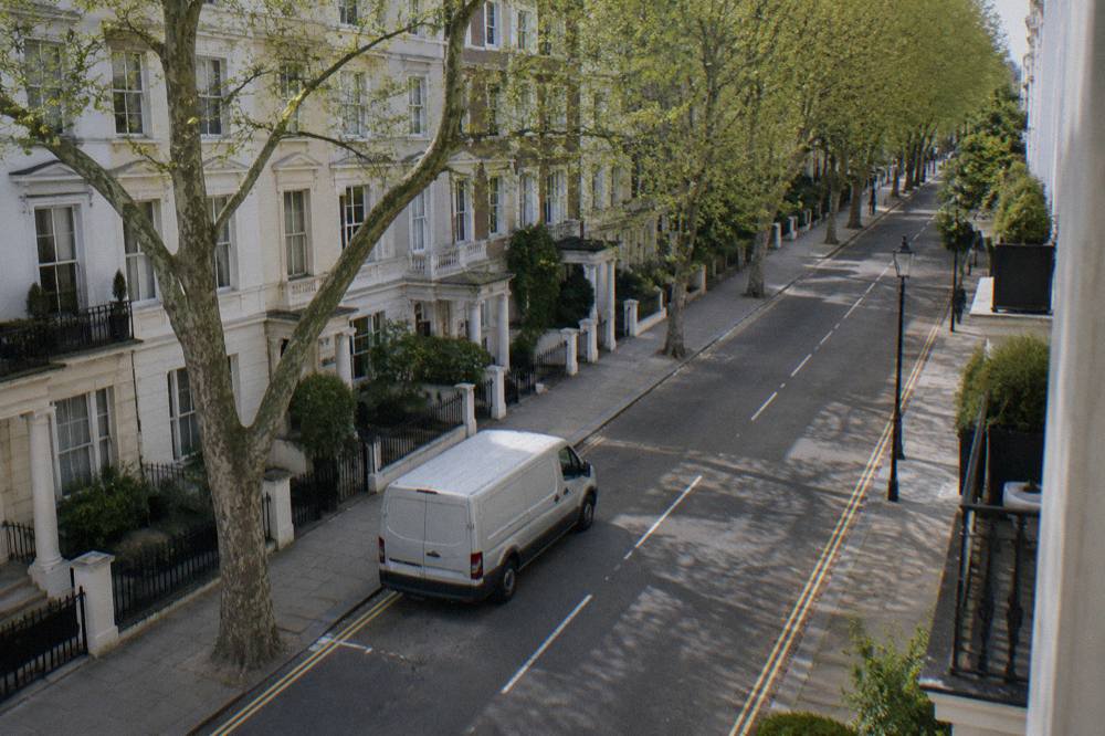 A wide west London street with white stucco terraced houses and plane trees