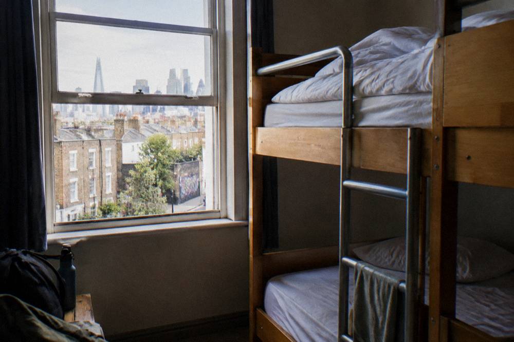 A hostel bunk dorm room with wooden frames and a ladder