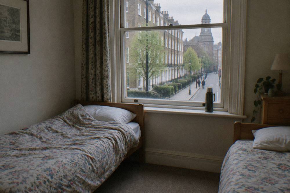 A small hotel twin room with two single beds and a window onto the street