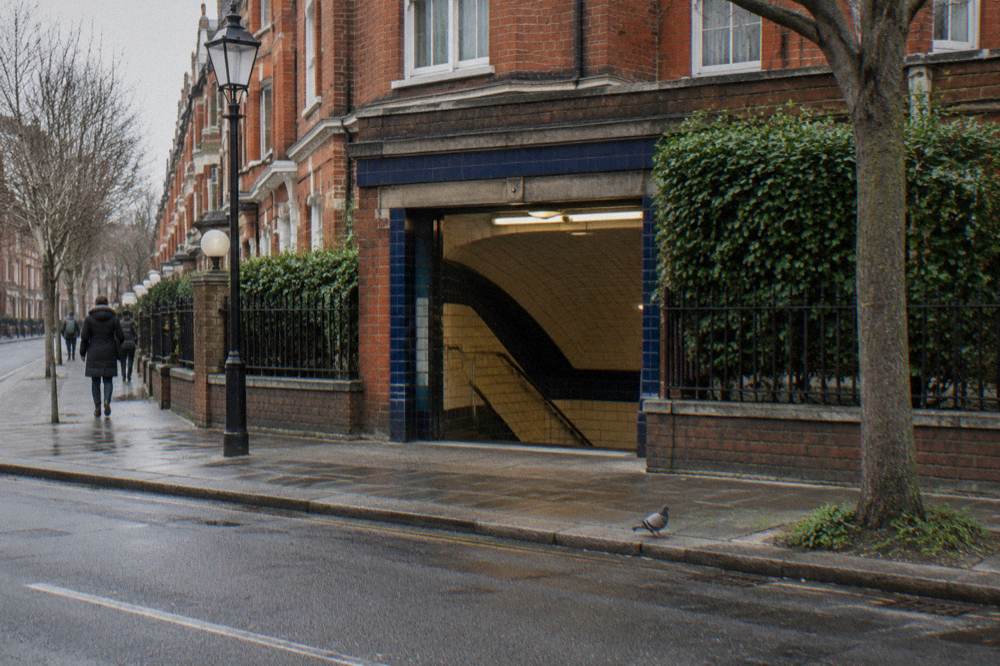 A London street corner with a tube station entrance and terraced buildings behind