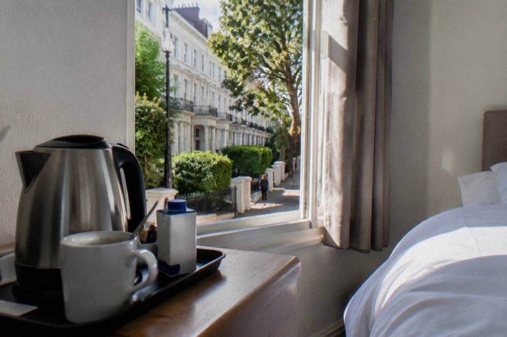A bright compact double room with a kettle tray on a bedside table