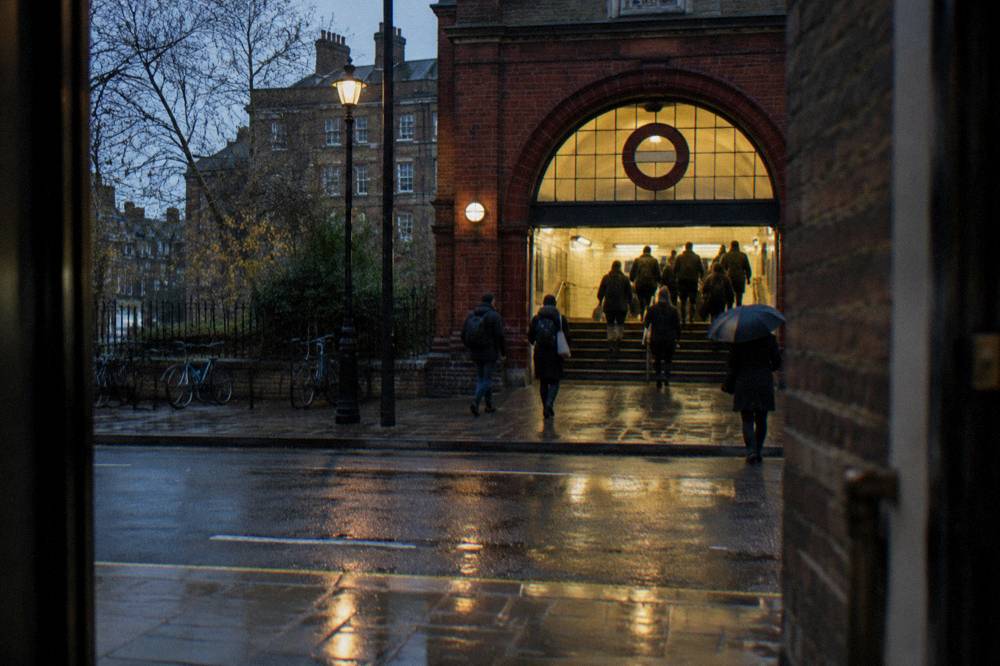 A London Underground station entrance on a busy street with a red brick building behind