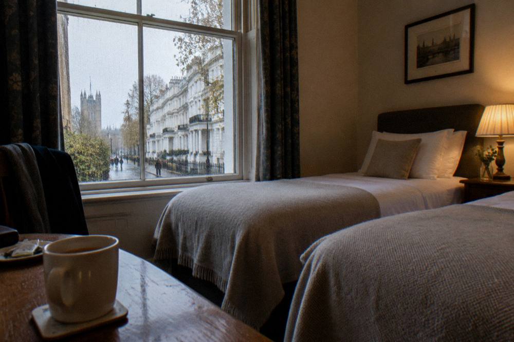 A tidy twin hotel room with two single beds, bedside table and window