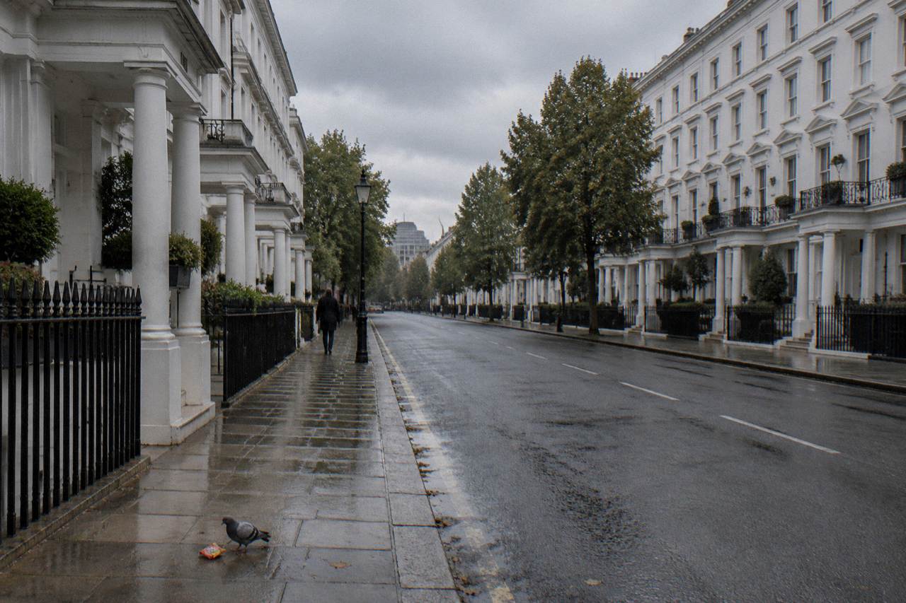 A London street of tall white townhouse buildings under an overcast sky