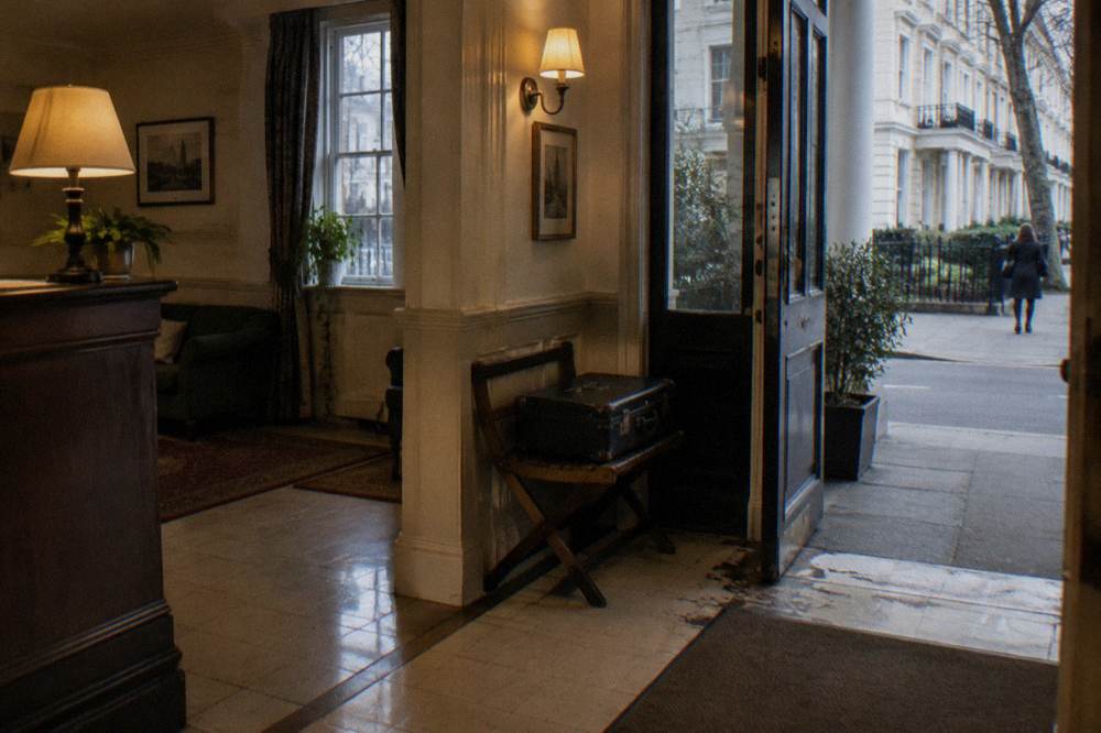 A tiled hotel lobby corner with a wooden luggage rack